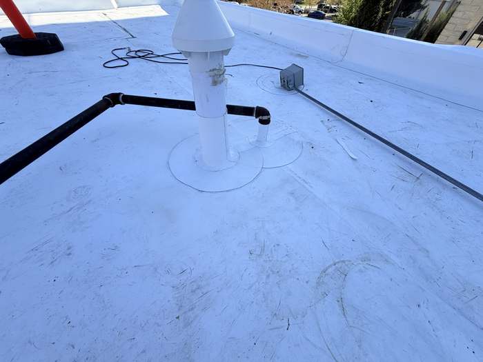 Crew sealing a roof penetration for waterproofing